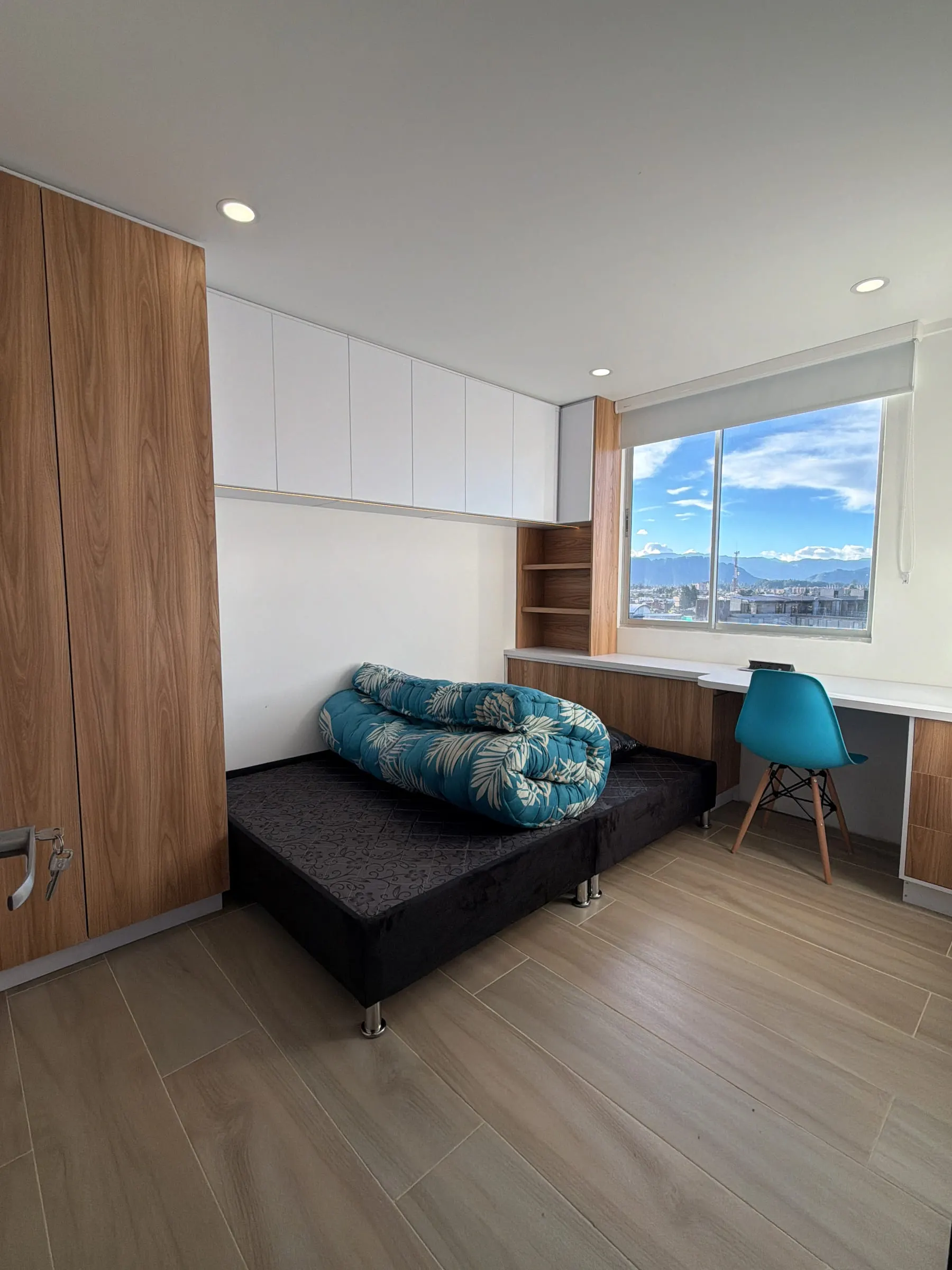 Habitación con clóset en madera, escritorio y ventanal.
