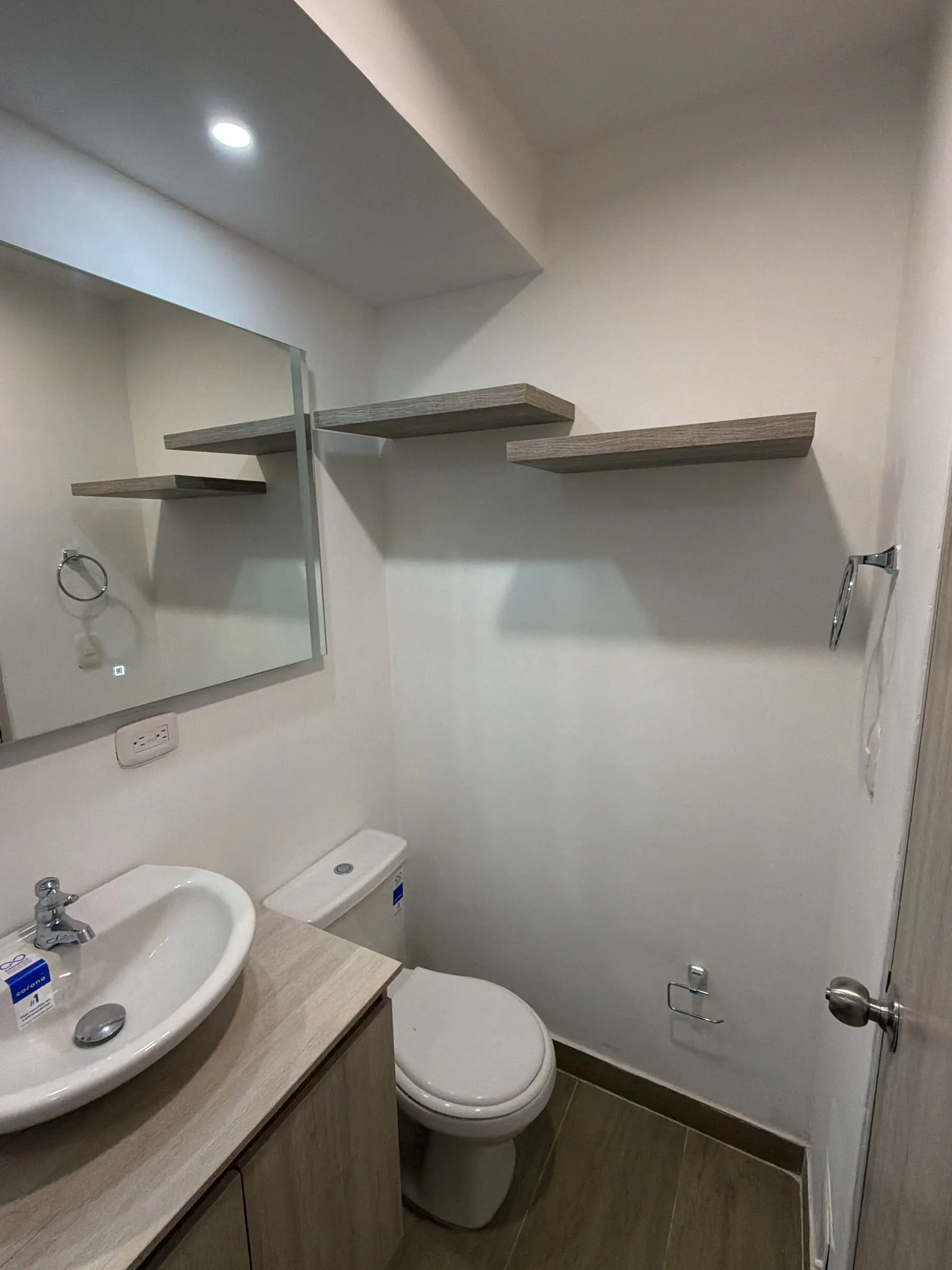 Baño con lavamanos, repisas voladas y espejo.