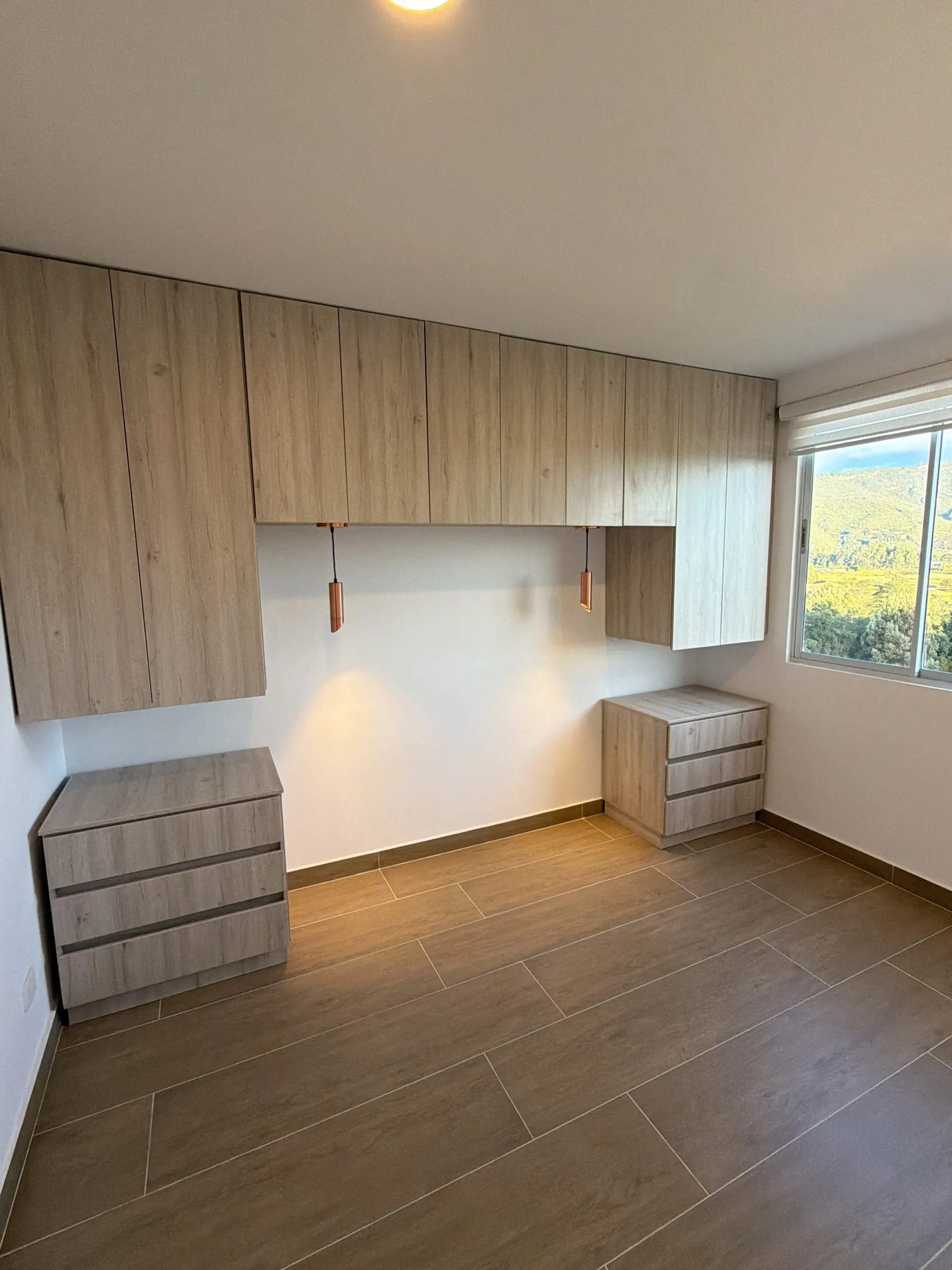 Habitación con carpintería en madera clara junto a la ventana.