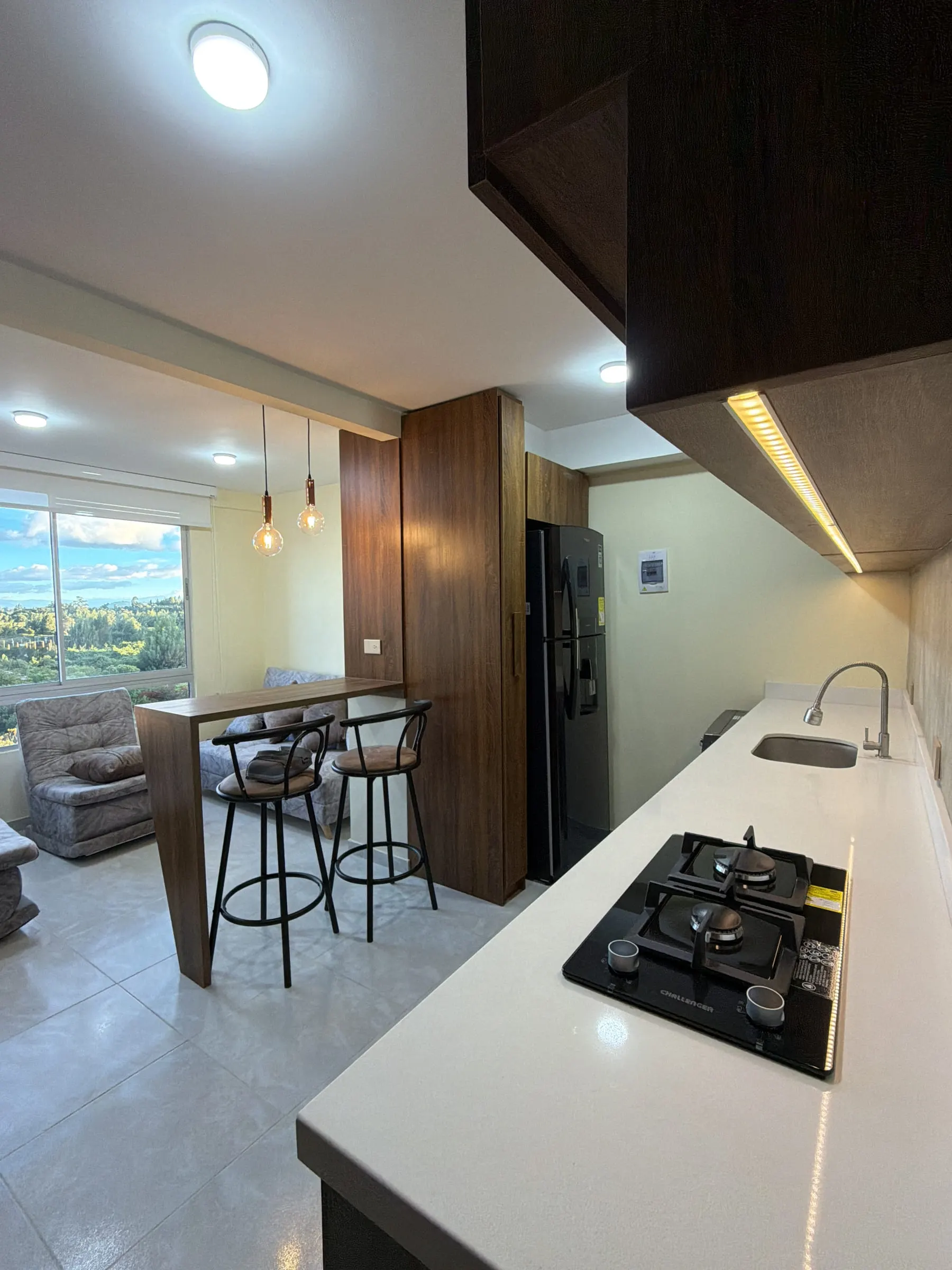 Cocina con mesones en superficie blanca y campana integrada.